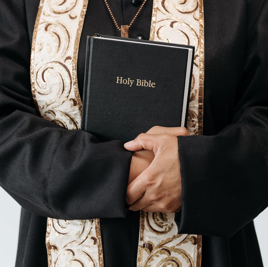 person standing in black long sleeve holding a holy bible